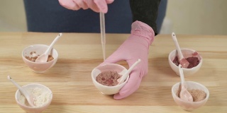 俯视图的一个女孩滴水在一个碗与草药粉末使用吸管。桌上放着有机草药粉的陶瓷碗。