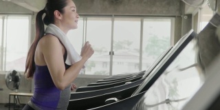 (慢动作)成熟的女人在跑步机上跑步，在健身房里做有氧运动。