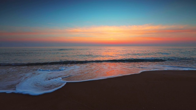 海面和海滩上的日出。海浪冲刷着沙滩