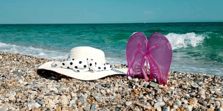 人字拖和一顶帽子在沙砾海滩上