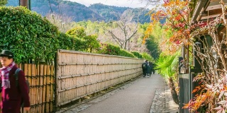 在日本京都的岚山竹林里，一群游客在散步