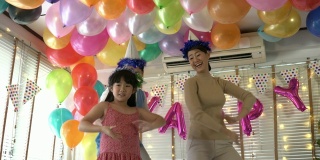 亚洲女儿喜欢在生日聚会上和爸爸妈妈一起跳舞。庆祝家庭幸福周年。节日与运动反应的概念。4 k决议。