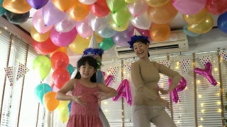 亚洲女儿喜欢在生日聚会上和爸爸妈妈一起跳舞。庆祝家庭幸福周年。节日与运动反应的概念。4 k决议。视频素材模板下载