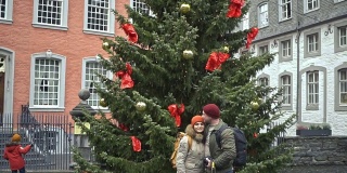 一对情侣站在圣诞树旁