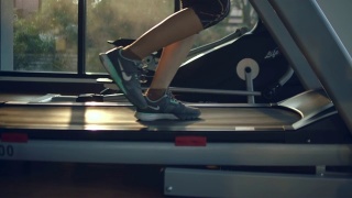 年轻的亚洲女人在跑步机上跑步视频素材模板下载
