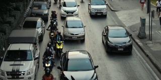 从上面俯瞰曼谷的交通，日落，汽车和公共汽车沿着道路行驶，自行车在其间穿梭。