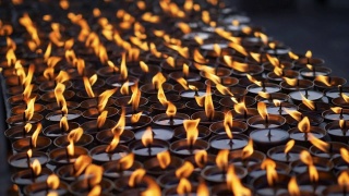 尼泊尔一座佛教寺庙旁点燃多支仪式蜡烛。慢动作特写镜头视频素材模板下载