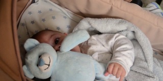可爱的3个月大的小男孩在婴儿床做鬼脸