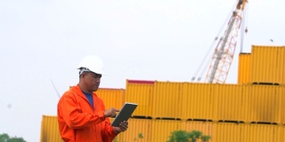 工程师使用数字平板电脑在港口的集装箱背景