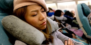 4K镜头:一名亚洲女子在飞机上试图睡觉。