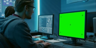 聪明的男性IT程序员在桌面绿色模拟屏幕电脑上工作。软件开发/代码编写/网站设计/数据库架构。技术部门办公室