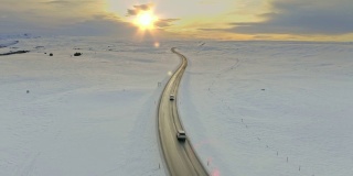 风景鸟瞰图的汽车驾驶通过一个冬天的乡村道路在日落
