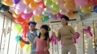 亚洲女儿喜欢在生日聚会上和爸爸妈妈一起跳舞。庆祝家庭幸福周年。节日与运动反应的概念。4 k决议。视频素材模板下载