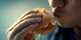 特写镜头里的人正在吃汉堡包。幸福的