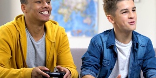 两个男性朋友在电子游戏中获胜，坐在沙发上，青少年的友谊