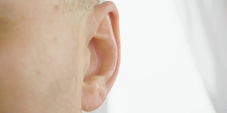 成年男性的耳朵靠近。男人在动他的耳朵。耳鼻喉科和听力健康