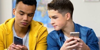 两个高中生在智能手机上浏览约会软件，选择女朋友