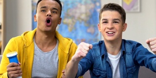 两个男孩在看电视上的足球比赛，唱着歌，吹着喇叭