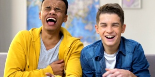 两个青少年笑着看电视上的喜剧电影，单口相声表演，情景喜剧