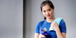 中等近距离的肖像微笑亚洲妇女疲惫后锻炼喝水从瓶子