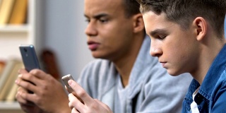 两个高中好友在智能手机上玩手机游戏，周末休闲