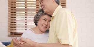 亚洲老夫妇在家里的客厅边听音乐边跳舞，甜蜜的夫妇在家里放松的时候边玩边享受爱的时刻。生活方式高级家庭放松居家理念。