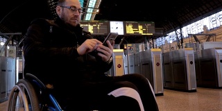 轮椅上的残疾人在火车站使用智能手机-股票视频