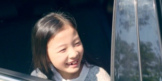 一个亚洲小女孩从汽车后窗往外看