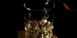 将威士忌倒入装有冰块的木桌玻璃杯中
