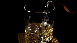将威士忌倒入装有冰块的木桌玻璃杯中视频素材模板下载