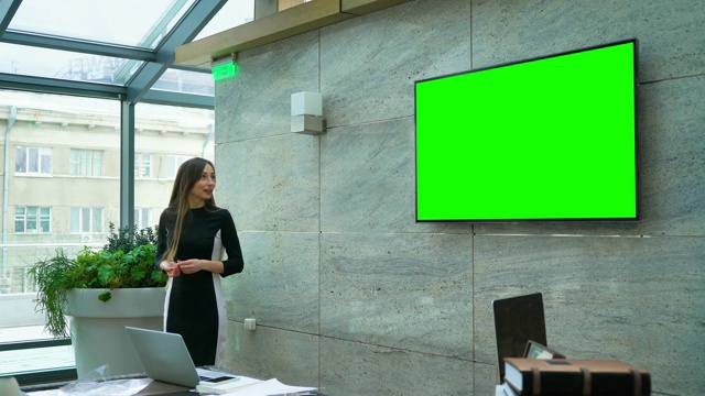 女商人在会议厅的绿色大屏幕上做报告