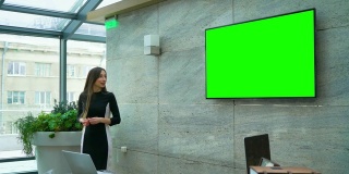 女商人在会议厅的绿色大屏幕上做报告