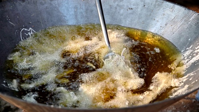 将炸好的芋头放入平底锅中，放入滚烫的油中炸开