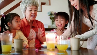 中国多代同堂的家庭在室内庆祝生日，一个小孩吹蜡烛在蛋糕上视频素材模板下载