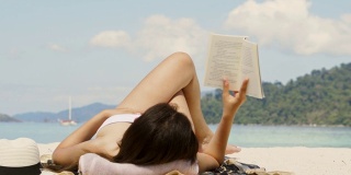暑假亚洲女人在海滩上读一本书在空闲时间假期