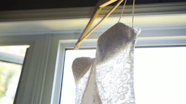 一个美丽的白色婚纱挂在窗口的特写