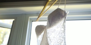 一个美丽的白色婚纱挂在窗口的特写