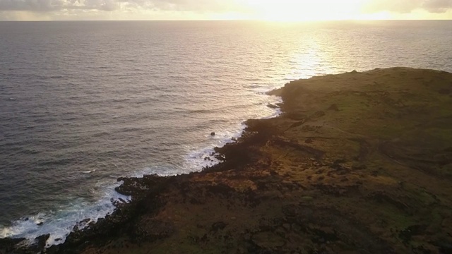 空中镜头。日出时，无人机在复活节岛悬崖上拍摄。在一个充满色彩的多云的日子里，太平洋撞击海岸线和太阳从地平线上升起的令人惊叹的景色
