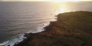 空中镜头。日出时，无人机在复活节岛悬崖上拍摄。在一个充满色彩的多云的日子里，太平洋撞击海岸线和太阳从地平线上升起的令人惊叹的景色