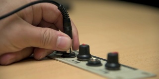 一只手把耳机插孔插进广播电台的演播室