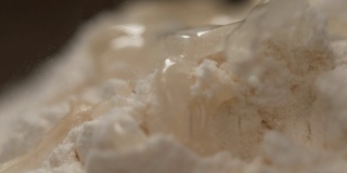 慢镜头，宏观镜头:透明液体从面包房的一堆面粉上流下。