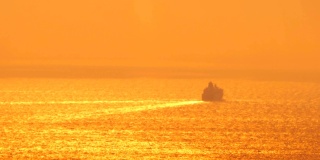 希腊圣托里尼岛，远处的游船轮廓在夕阳中远去。