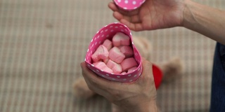 女人的手打开礼品盒，粉红色的棉花糖，心形