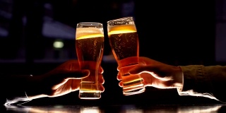 男性朋友们敲着啤酒杯，在一周的辛苦工作后放松一下，晚上