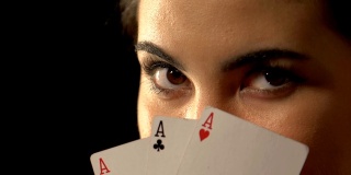 美女躲在扑克牌扑克牌组合的三张王牌后面，胜利的概念