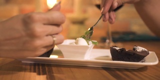浪漫的情侣在晚餐餐厅用勺子吃冰淇淋甜点。男人和女人在舒适的咖啡馆吃着甜点，冰淇淋和巧克力蛋糕