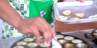 在泰国乌泰他尼省，女性烹饪泰国传统的当地甜点(Kanom Krok)。