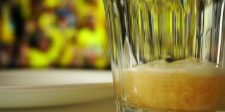 啤酒和零食。喝着啤酒，吃着开心果看足球。啤酒倒进玻璃杯里，开心果倒进盘子里。