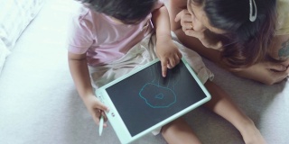 孩子坐在床上用数码板画画。