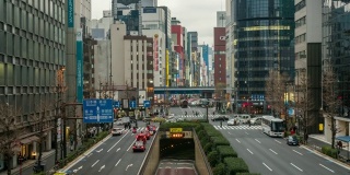 在日本东京新桥车站，一群不明身份的人在人行道上行走，路上有车流和隧道。日本霓虹街文化与购物概念